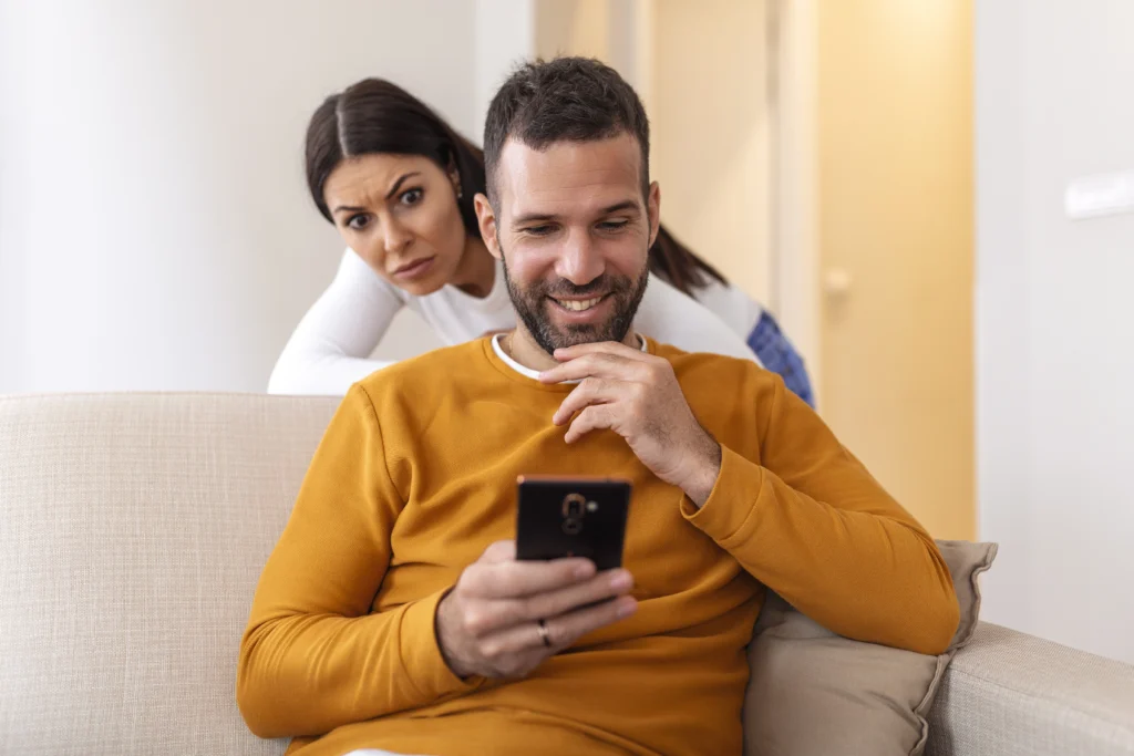 Femme suspectant son mari d’infidélité en regardant son téléphone – divorce pour adultère