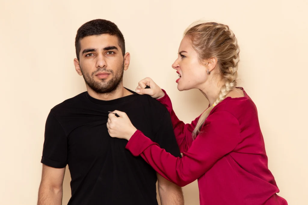 Femme en colère agrippant son partenaire lors d’une dispute, symbole de la jalousie maladive et de ses effets destructeurs sur le couple.