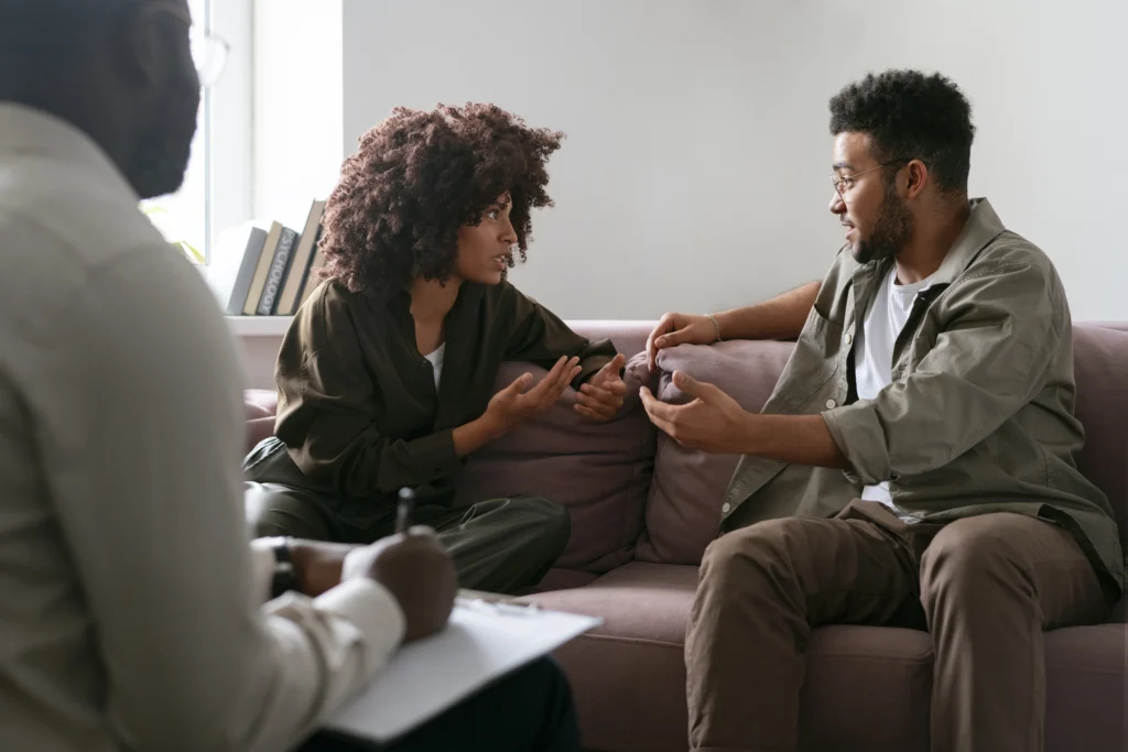 Un couple en discussion avec un thérapeute, symbole de la psychologie du couple, de la communication et de la reconstruction après des conflits.